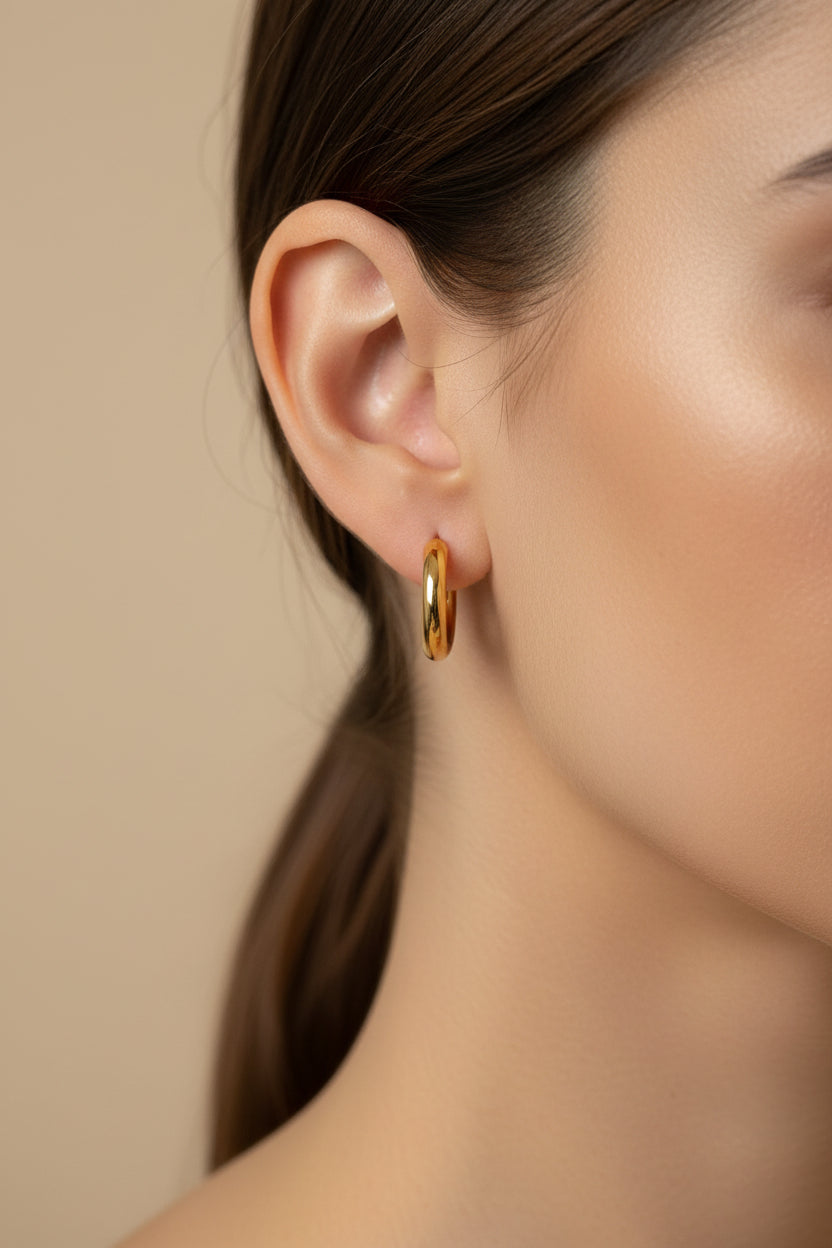 Gold hoop earrings on a textured gray surface