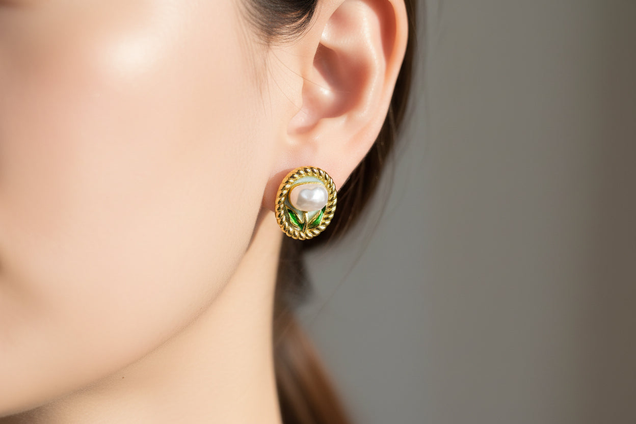 Gold earrings with gemstones on a beige surface