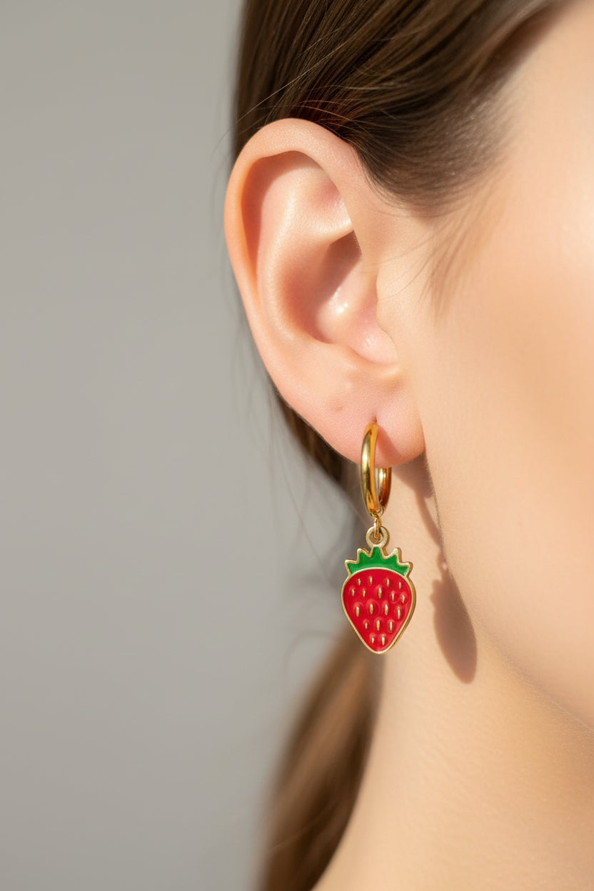 Two strawberry-shaped keychains on a pink jewelry box.