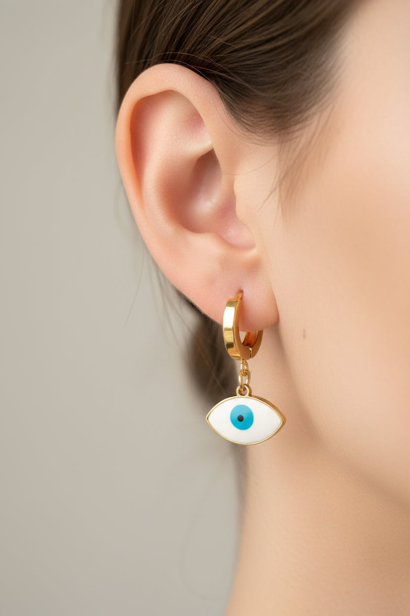 Gold earrings with blue eyes on a pink jewelry tray